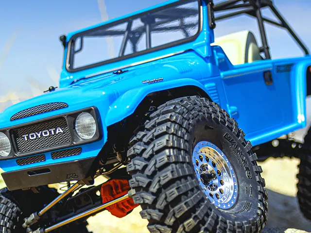 A blue scale rock crawler climbing on wide lugged tires